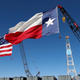 A Texas and American flag fly over oil trucks.